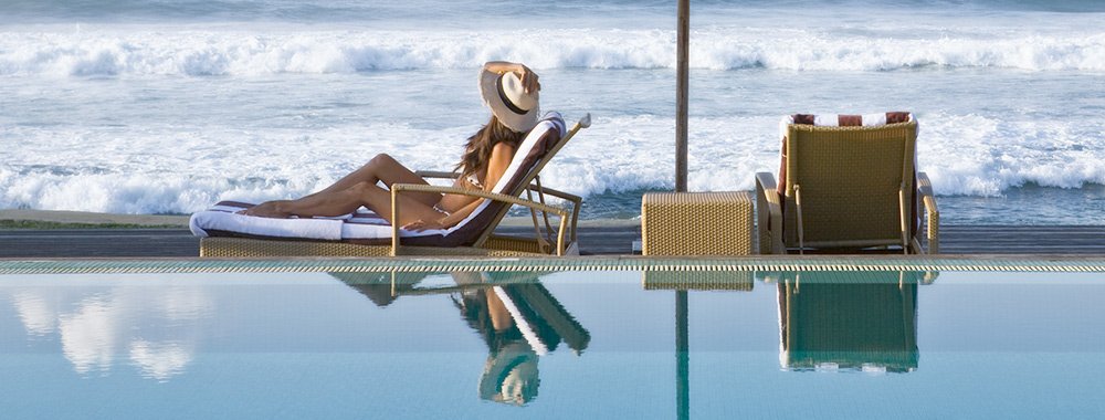 A lady relaxing by the infinity poolside enjoying Beach